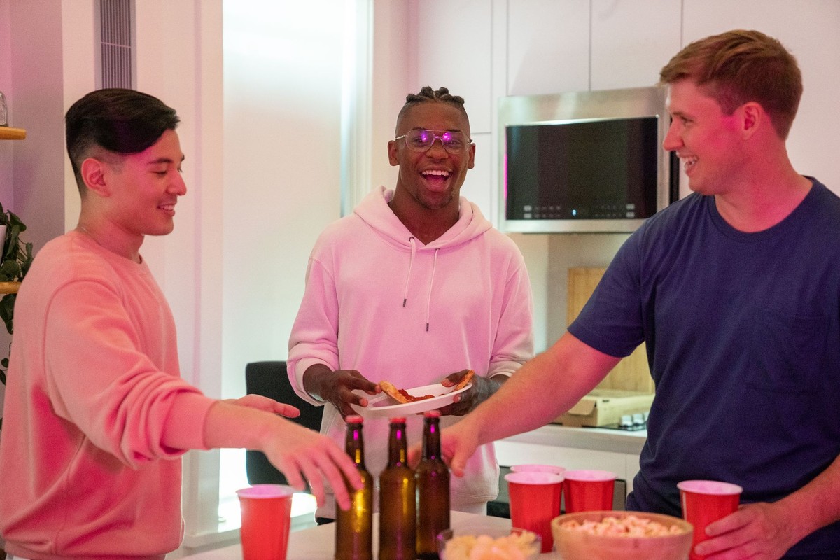 Three men talking and laughing together around a kitchen table