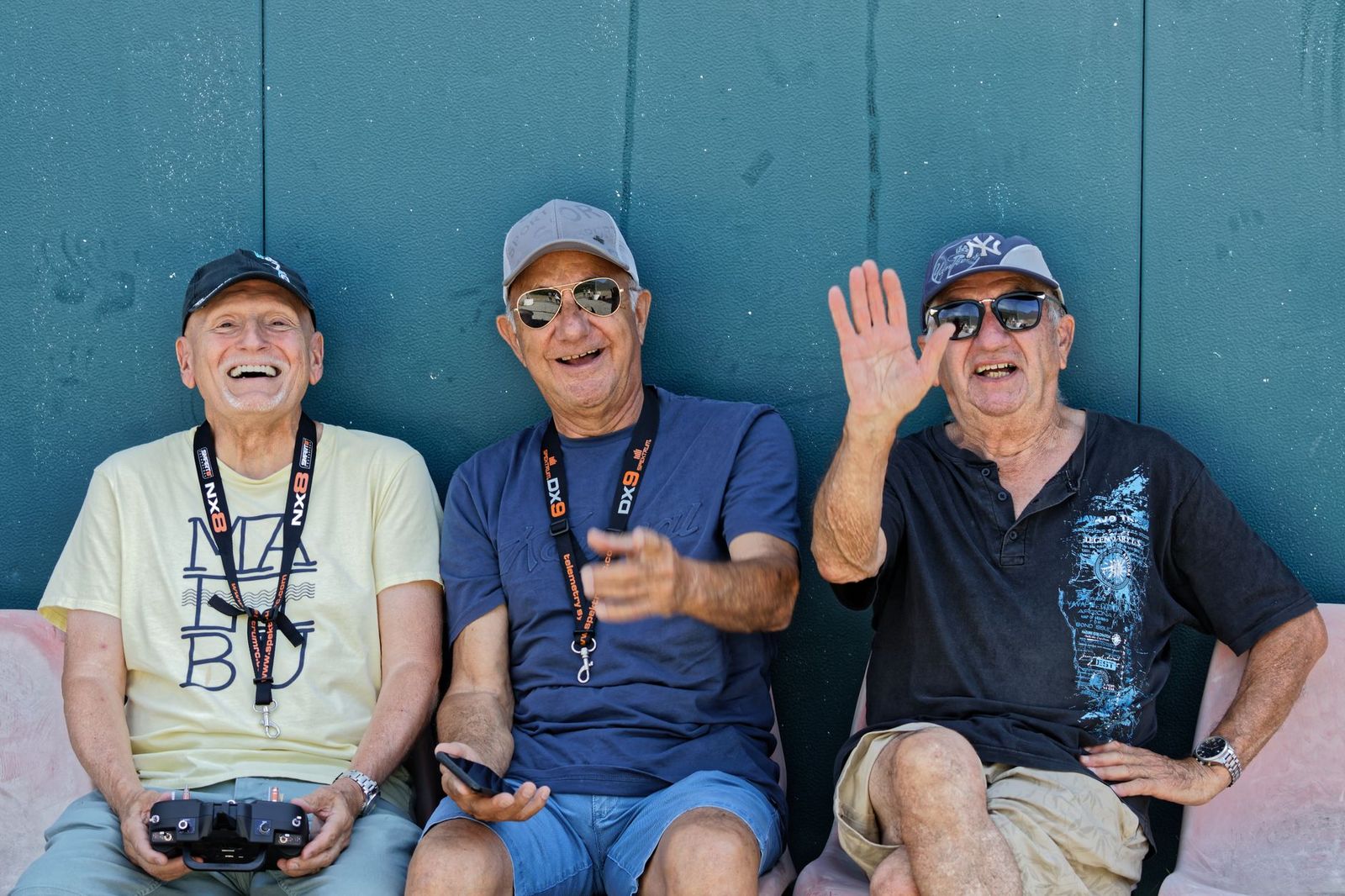 A group of older men laughing together against a wall